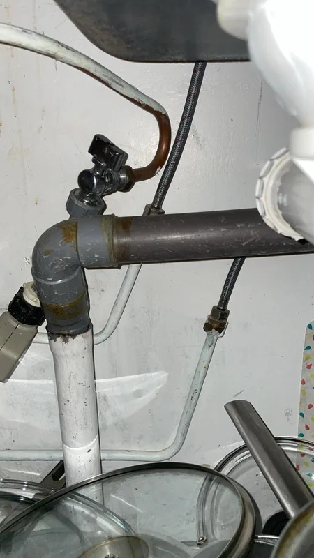 Robinet d'arrêt et évacuation PVC sous un évier de cuisine